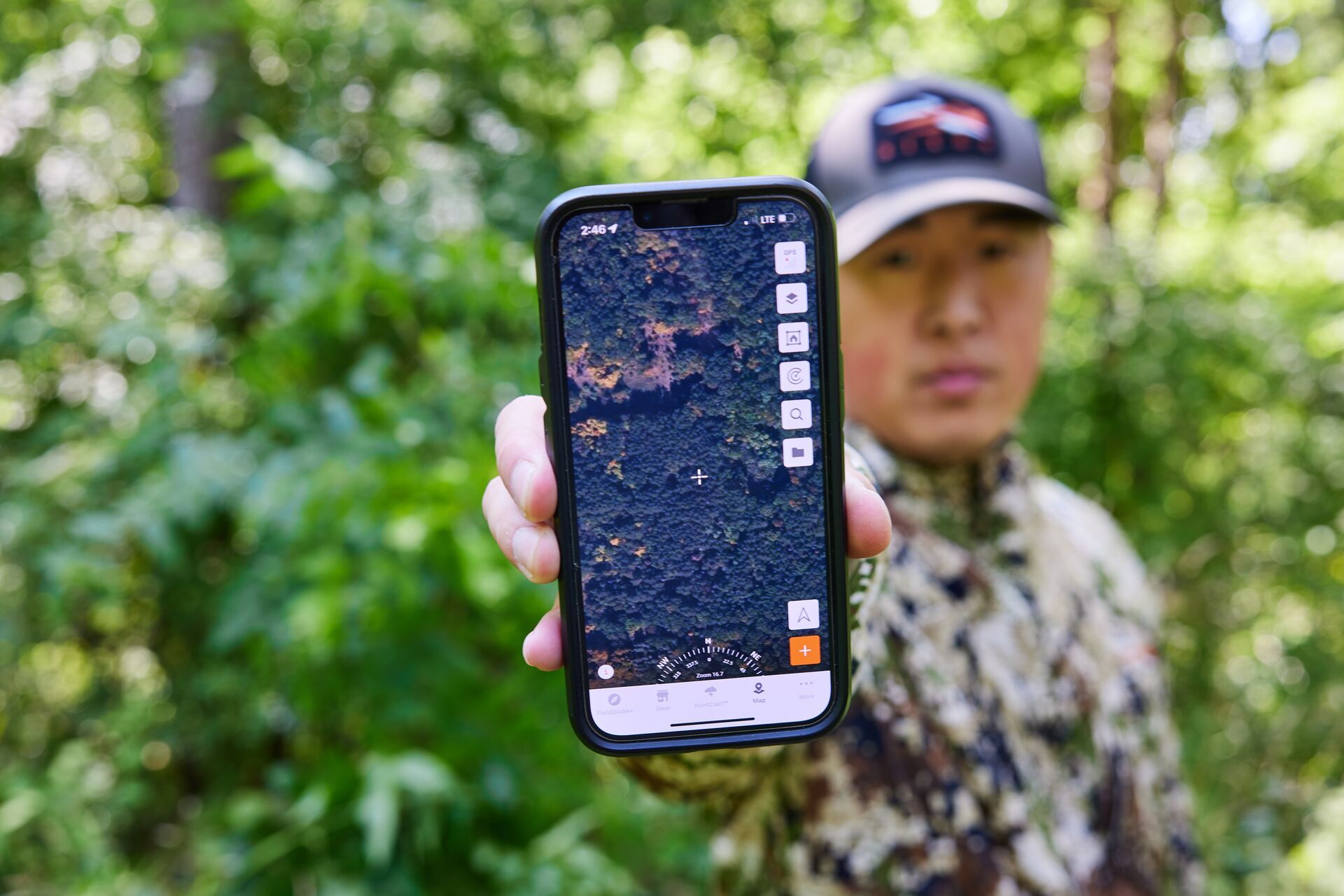 A hunter holds a phone to the camera showing HuntWise on screen.