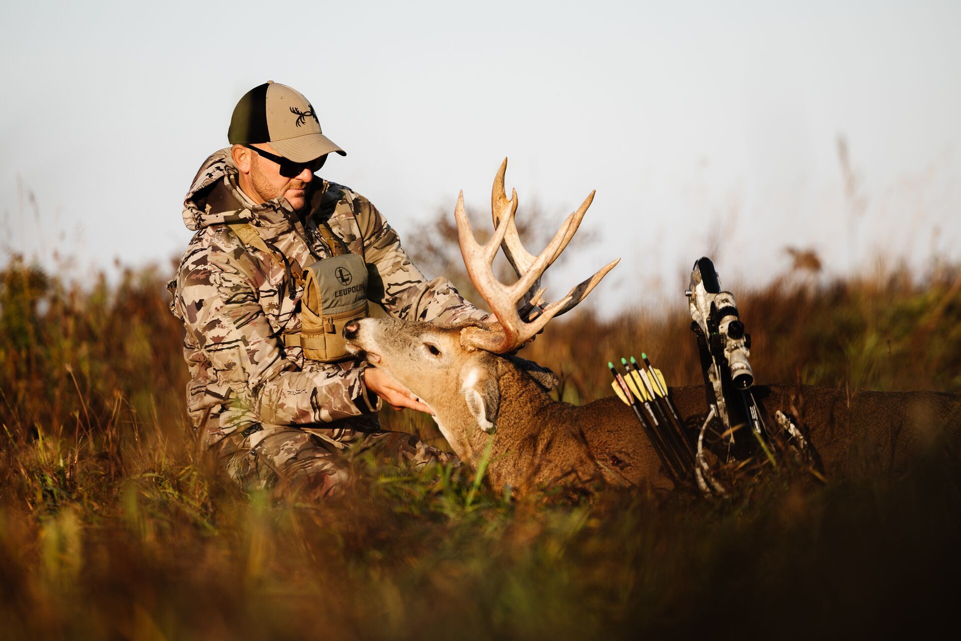 A hunter admires a buck deer on the ground after hunt. 