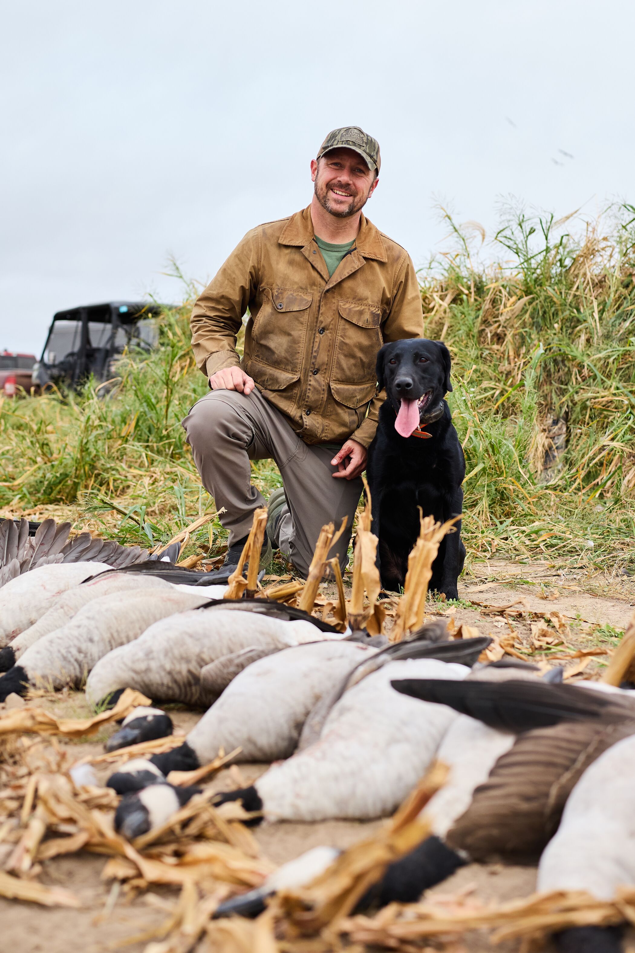Hunter with dog and goose harvest after hunt.
