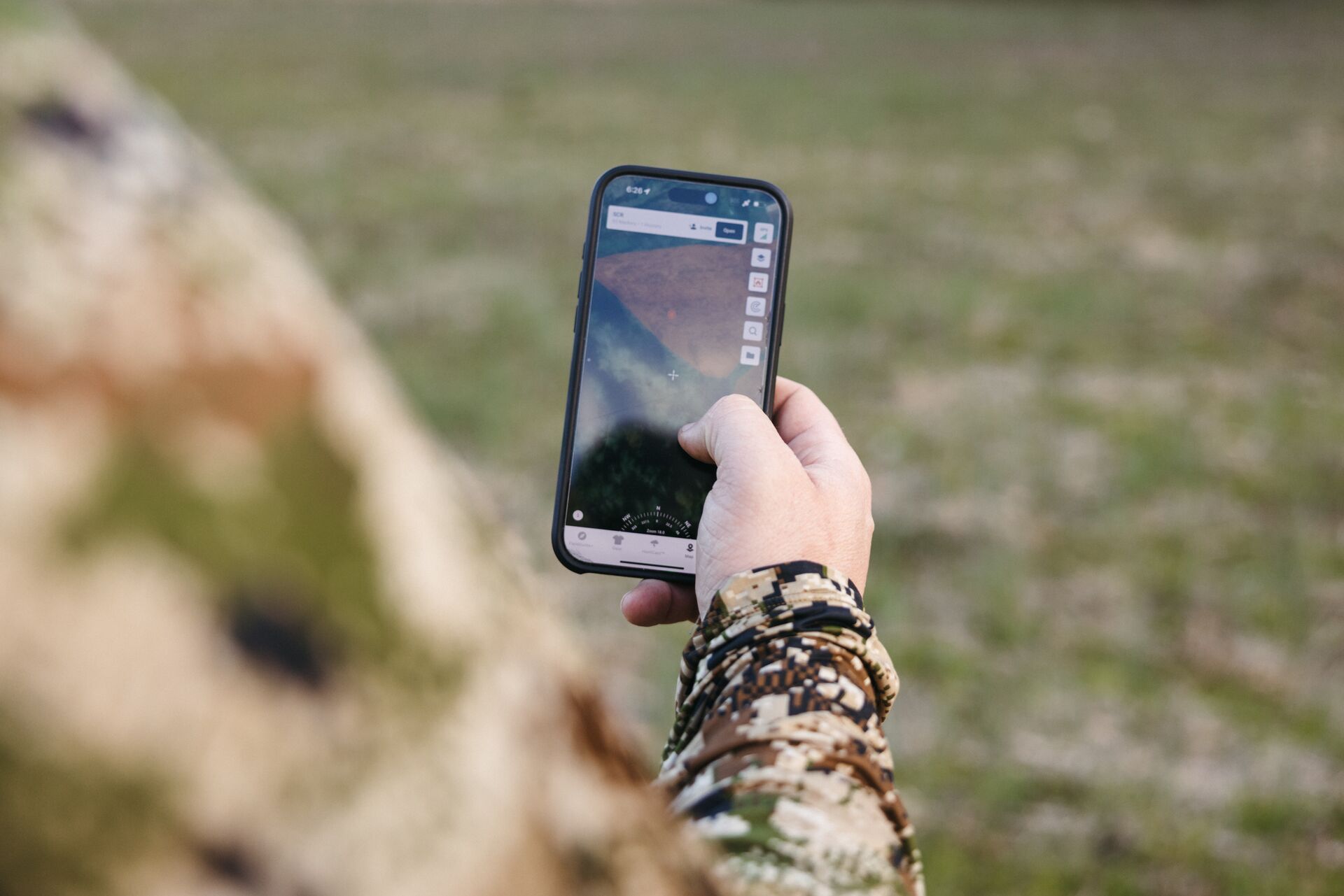 Hunter looking at phone to use topographic map app HuntWise. 