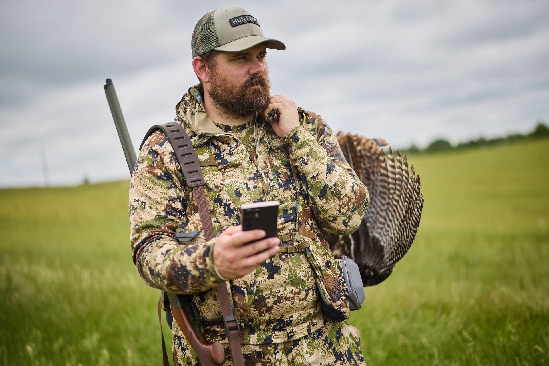 Hunter with turkey gear and phone for HuntWise turkey scouting.