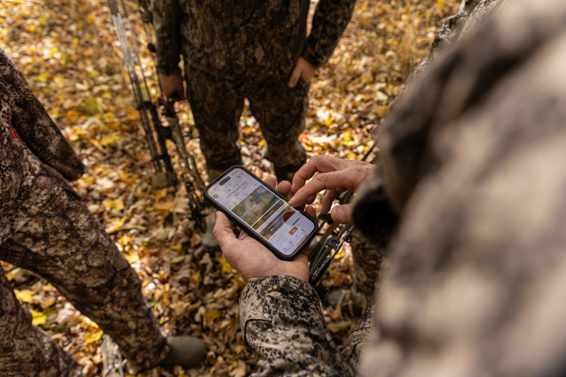 Hunters look at a phone screen showing the HuntWise hunting app. 