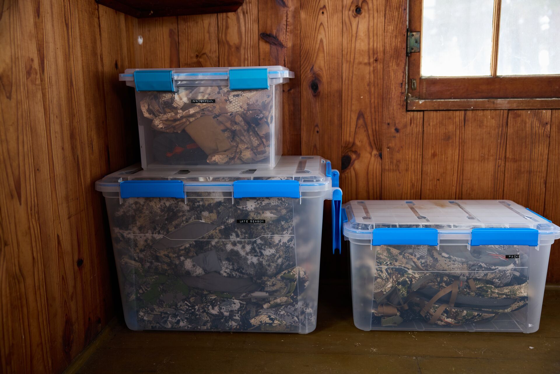 Hunting gear storage containers stacked against a wall. 