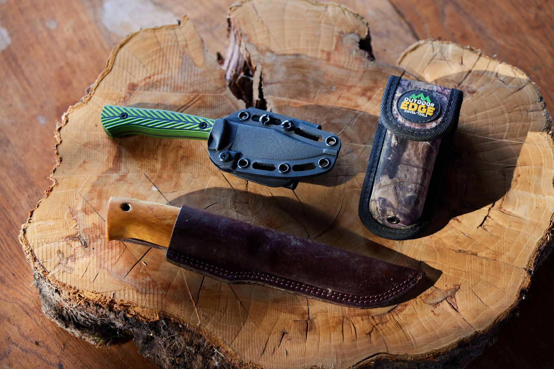 Three hunting knives sitting on block of wood. 