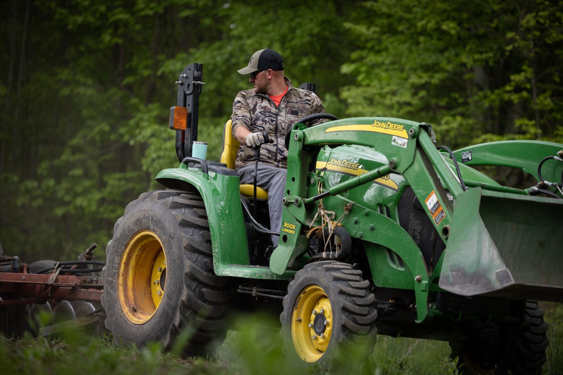 Man on tractor clearing land, how to get permission to hunt private land concept. 