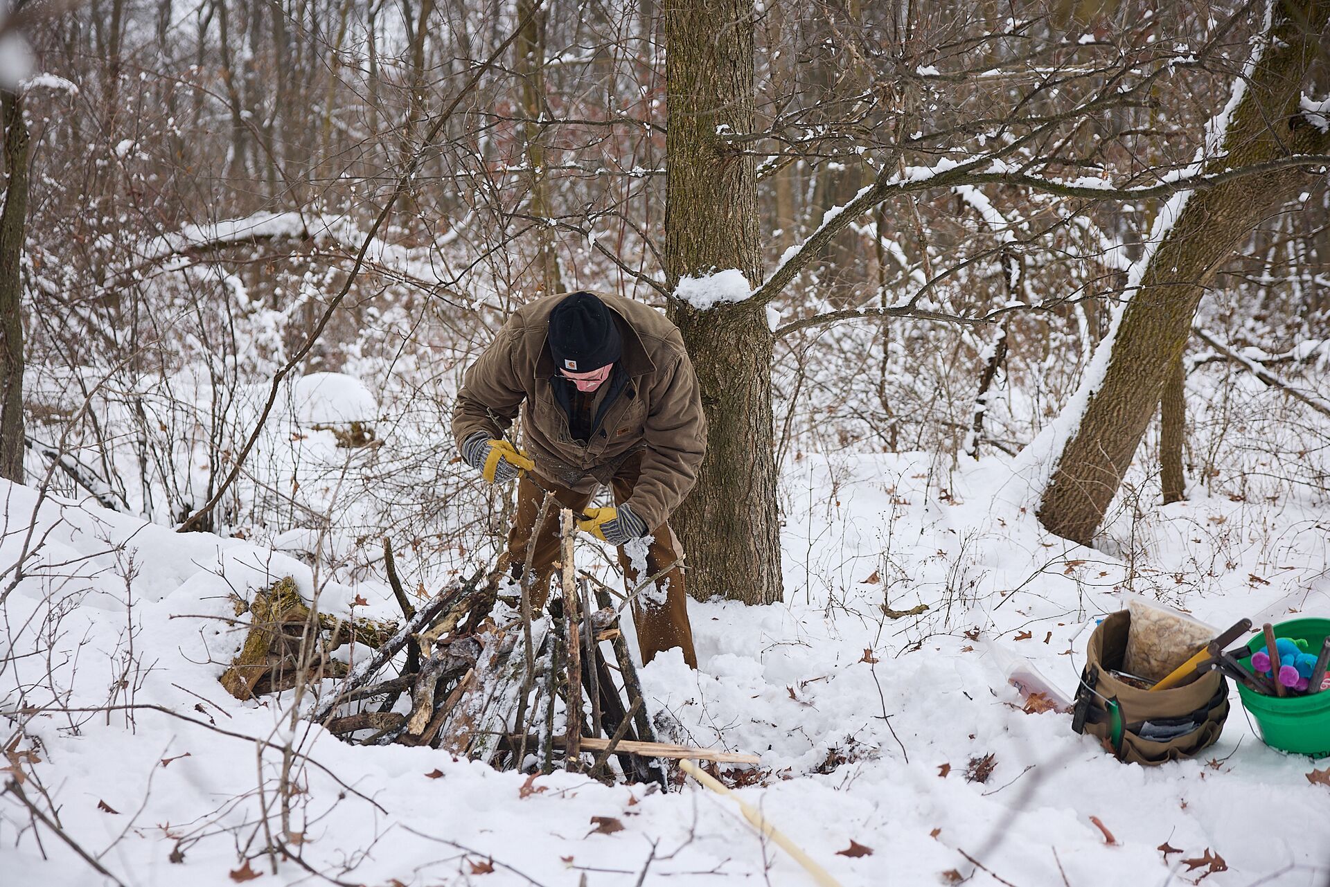 Man sets a trap in the snow, trapping for beginners concept.