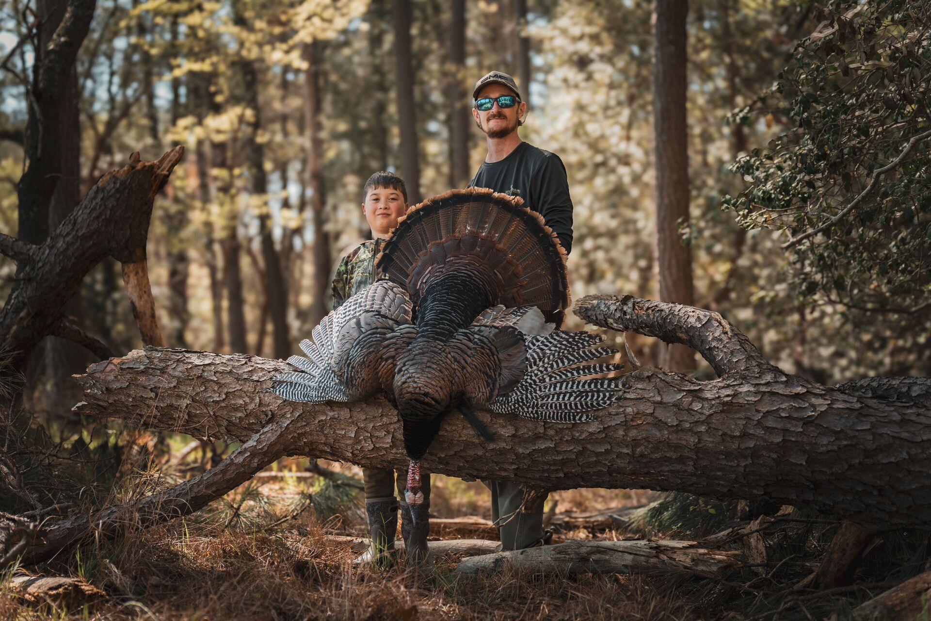 Man and boy smile with turkey after hunt, turkey hunting season success concept. 