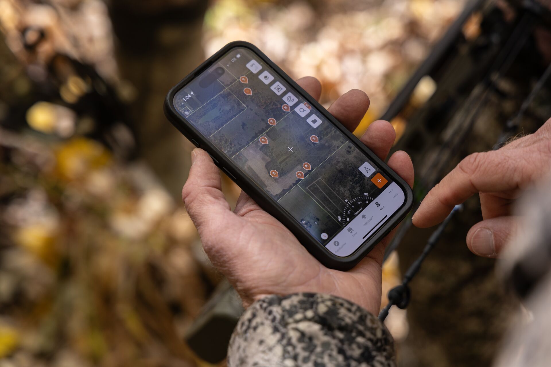 Close-up of a phone in a hunter's hand showing the HuntWise hunting app, deer hunting concept. 