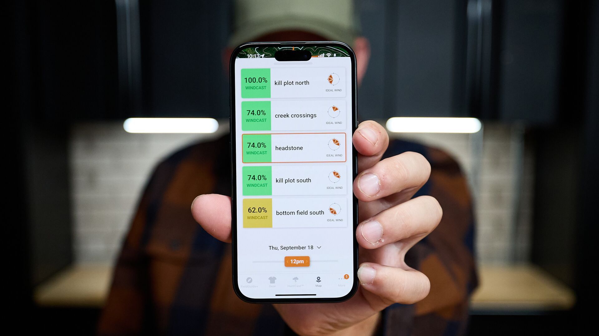 Hunter holding up a phone showing HuntWise WindCast on screen. 
