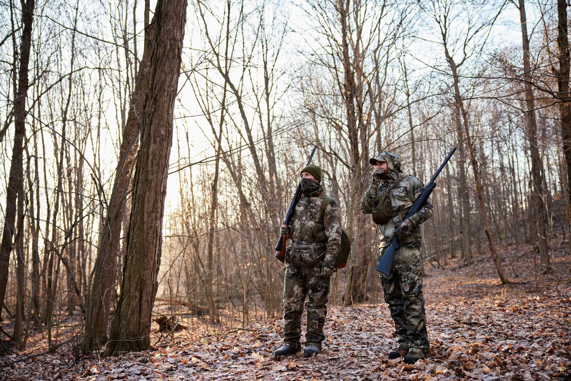 Two hunters in the woods calling and hunting turkeys.