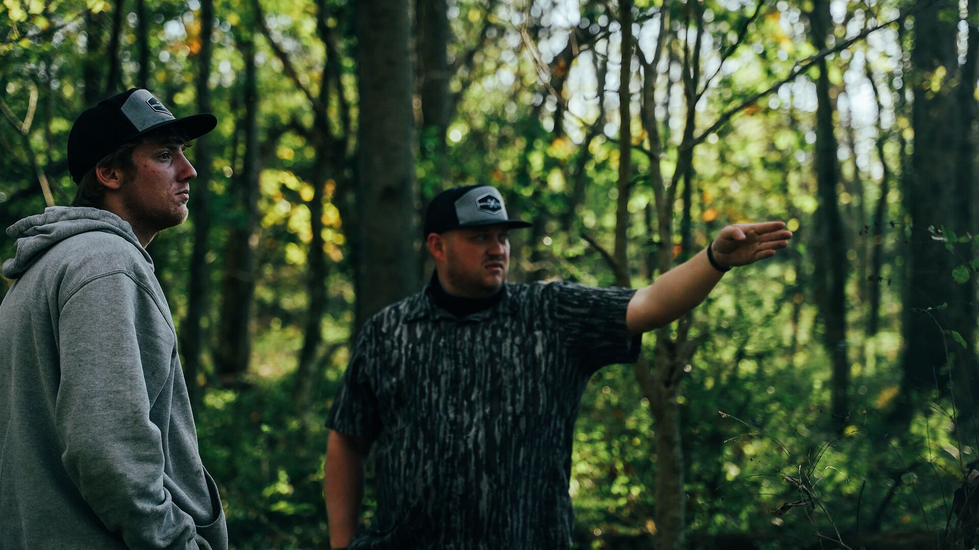 Two hunters talking and pointing in the woods, where can I hunt near me concept. 