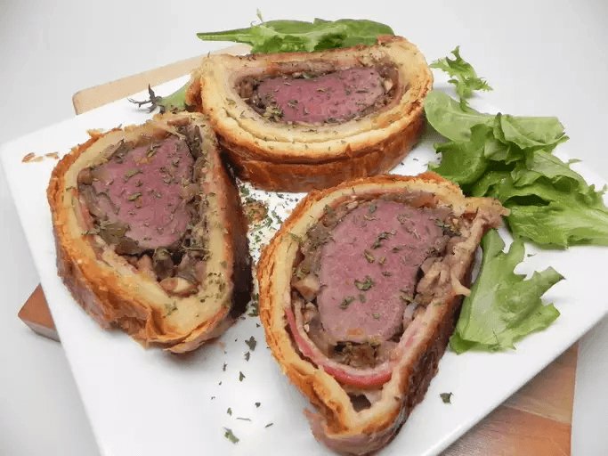 A photo of venison wellington on a white plate. 