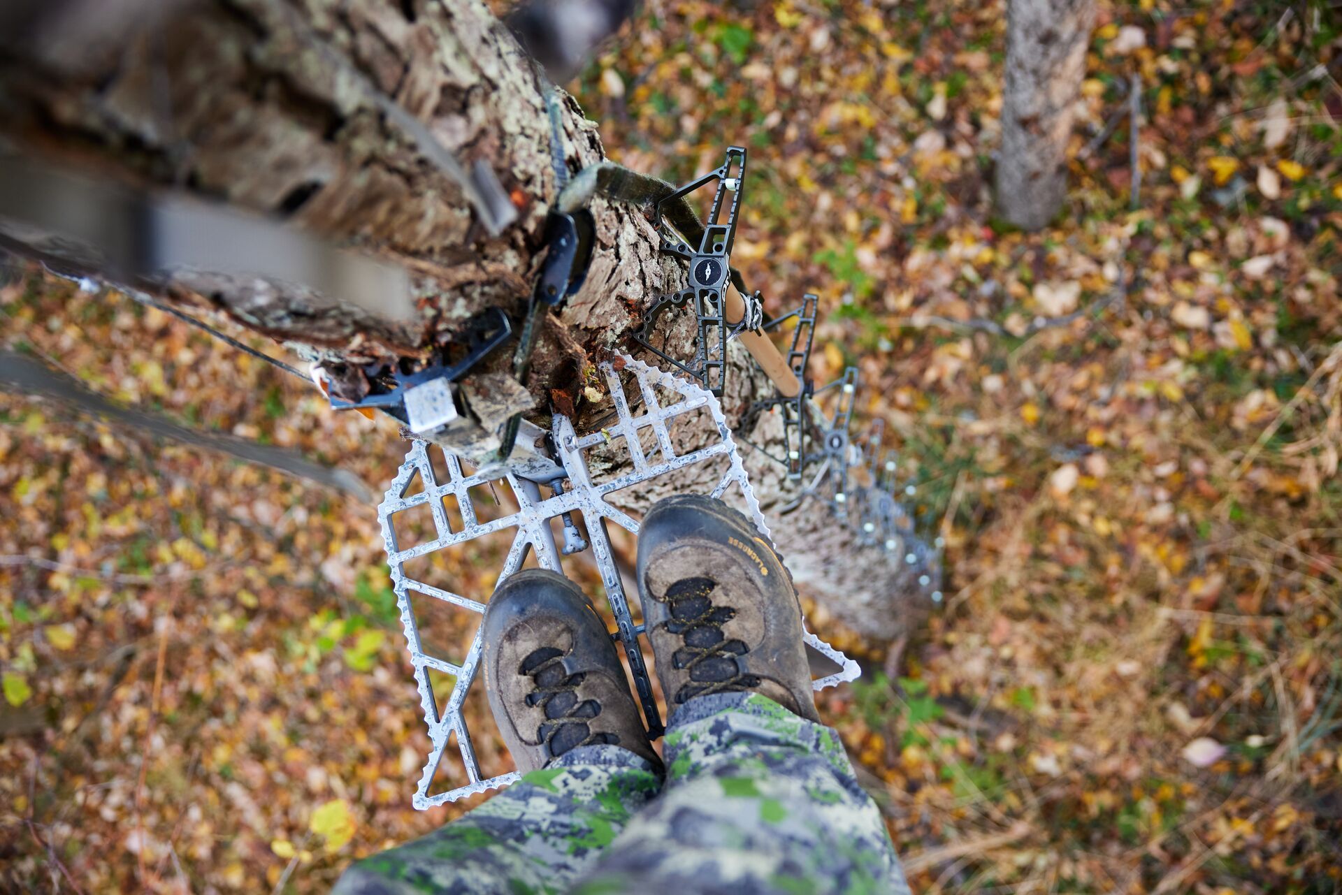 View looking down at feet on a tree saddle platform. 