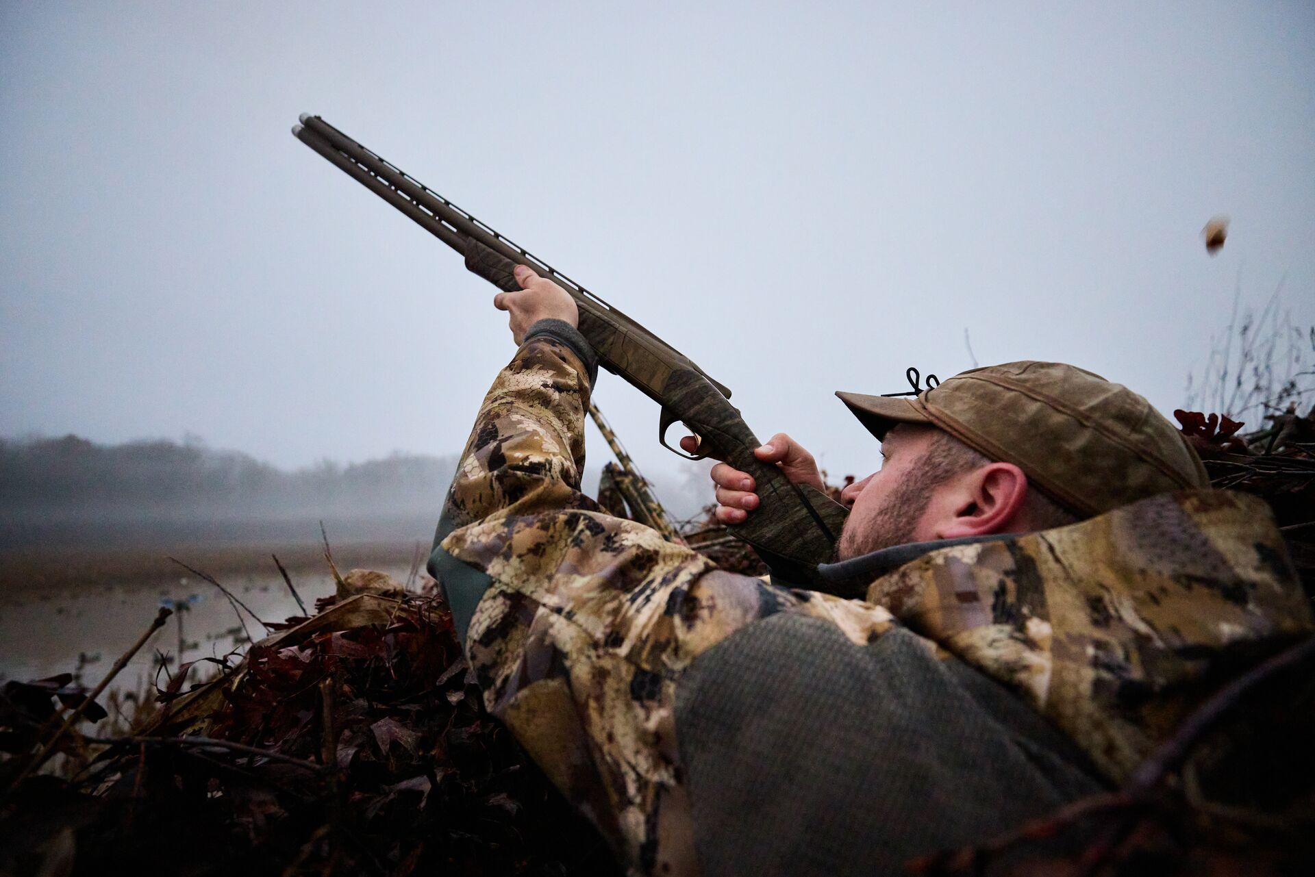Hunter aims shotgun while waterfowl hunting