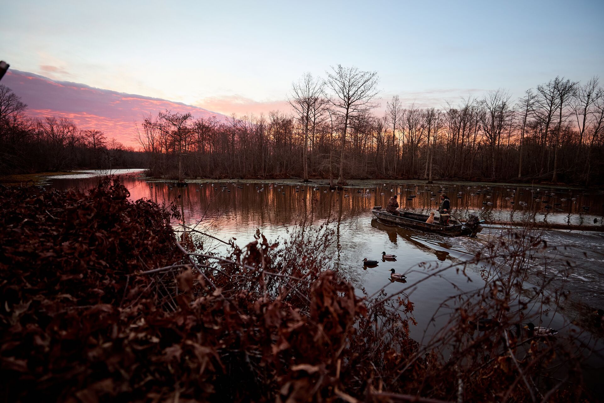 Wide shot of boat with hunters on water, use WindCast hunting app concept. 