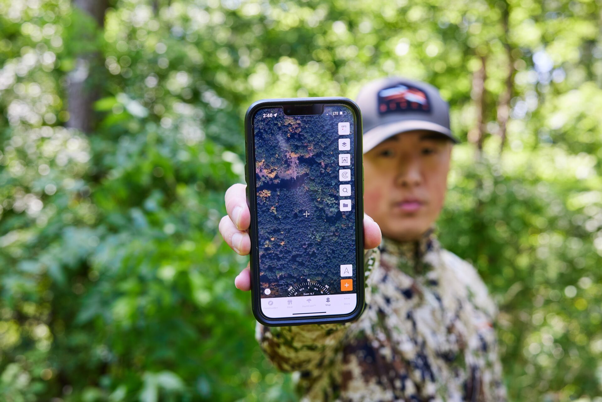 A hunter holds a phone up featuring the HuntWise app, e-scout and prepare for archery season concept. 