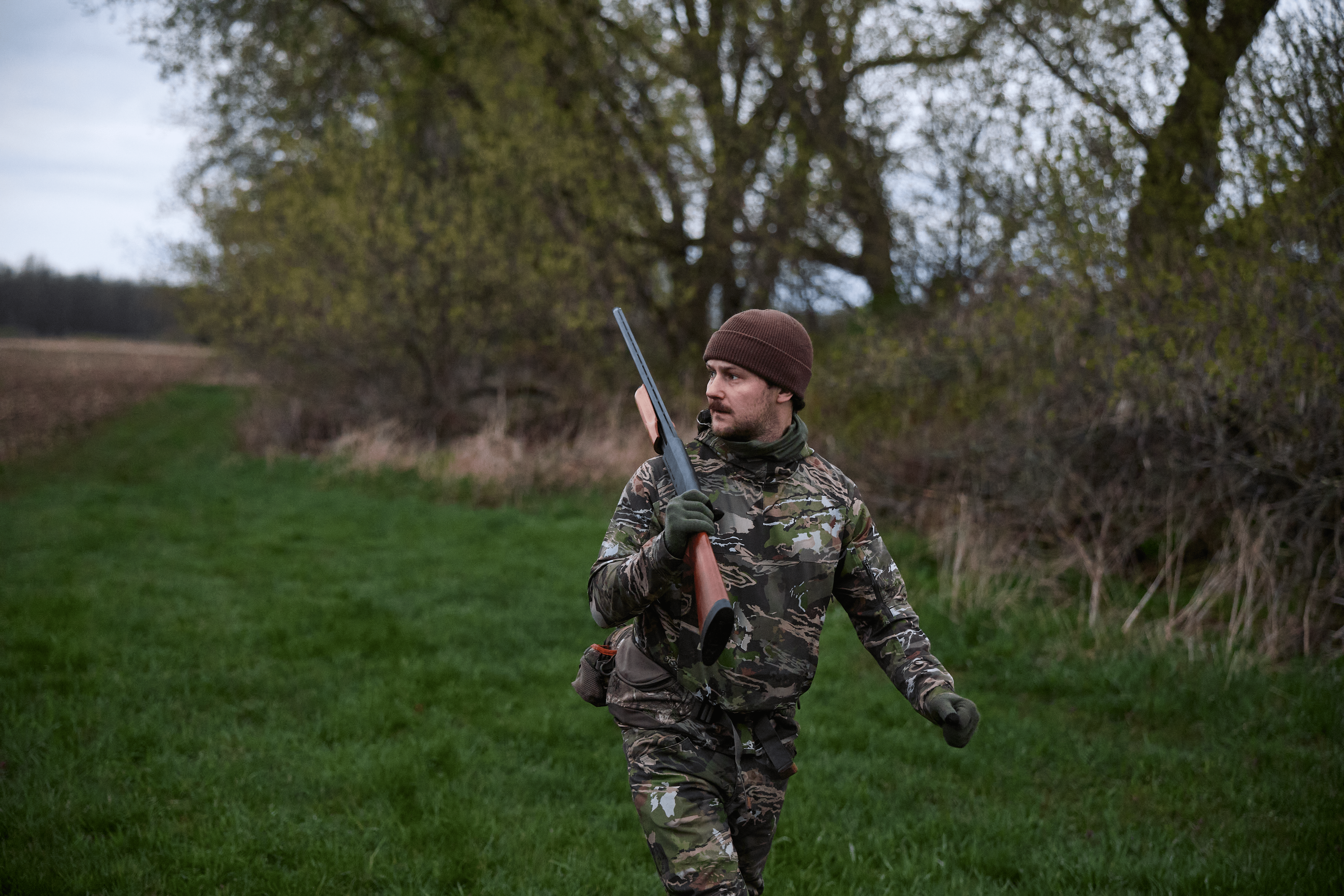 A hunter in camo carries a firearm, Ohio hunting concept. 