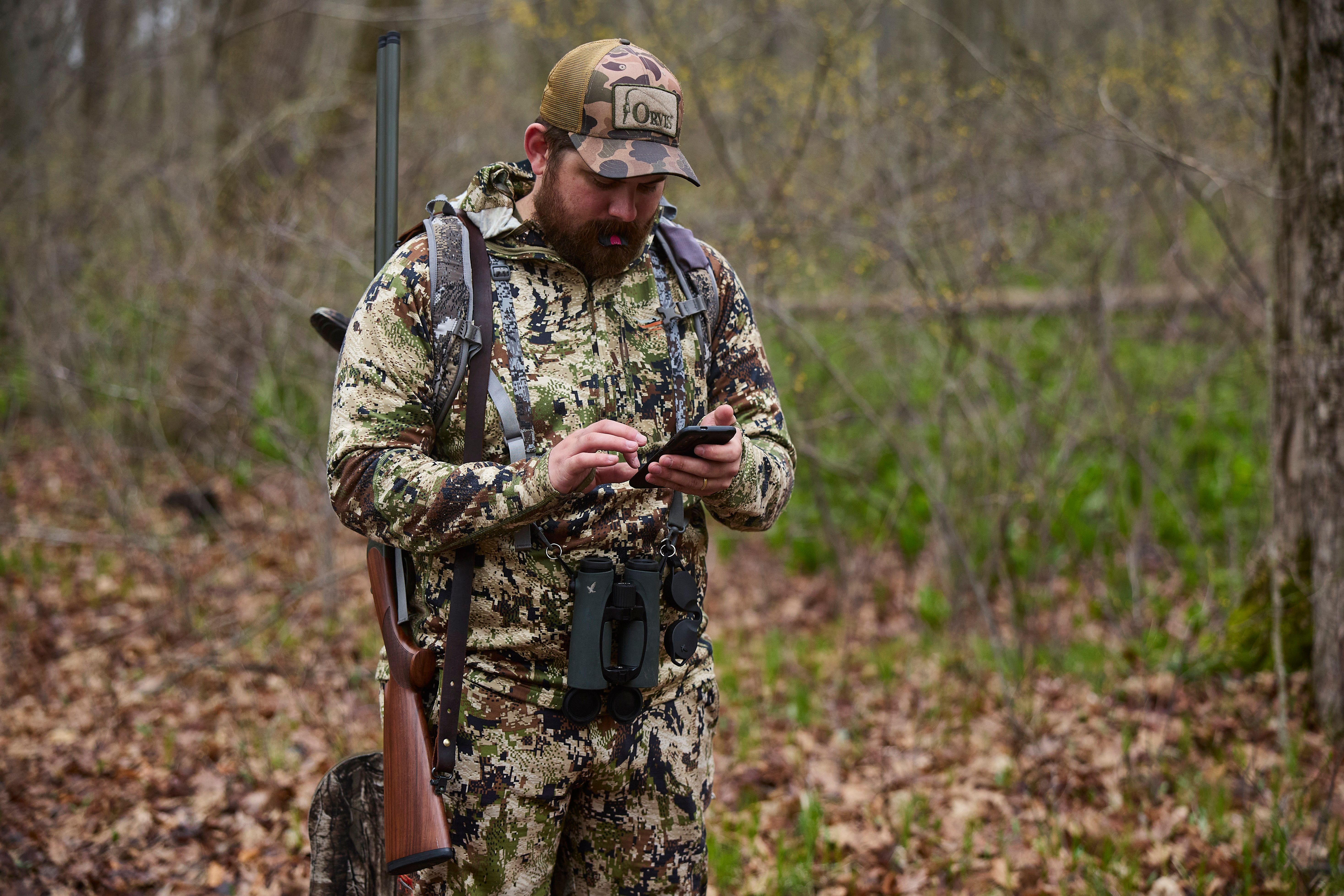 A hunter uses binoculars to scout for turkeys.