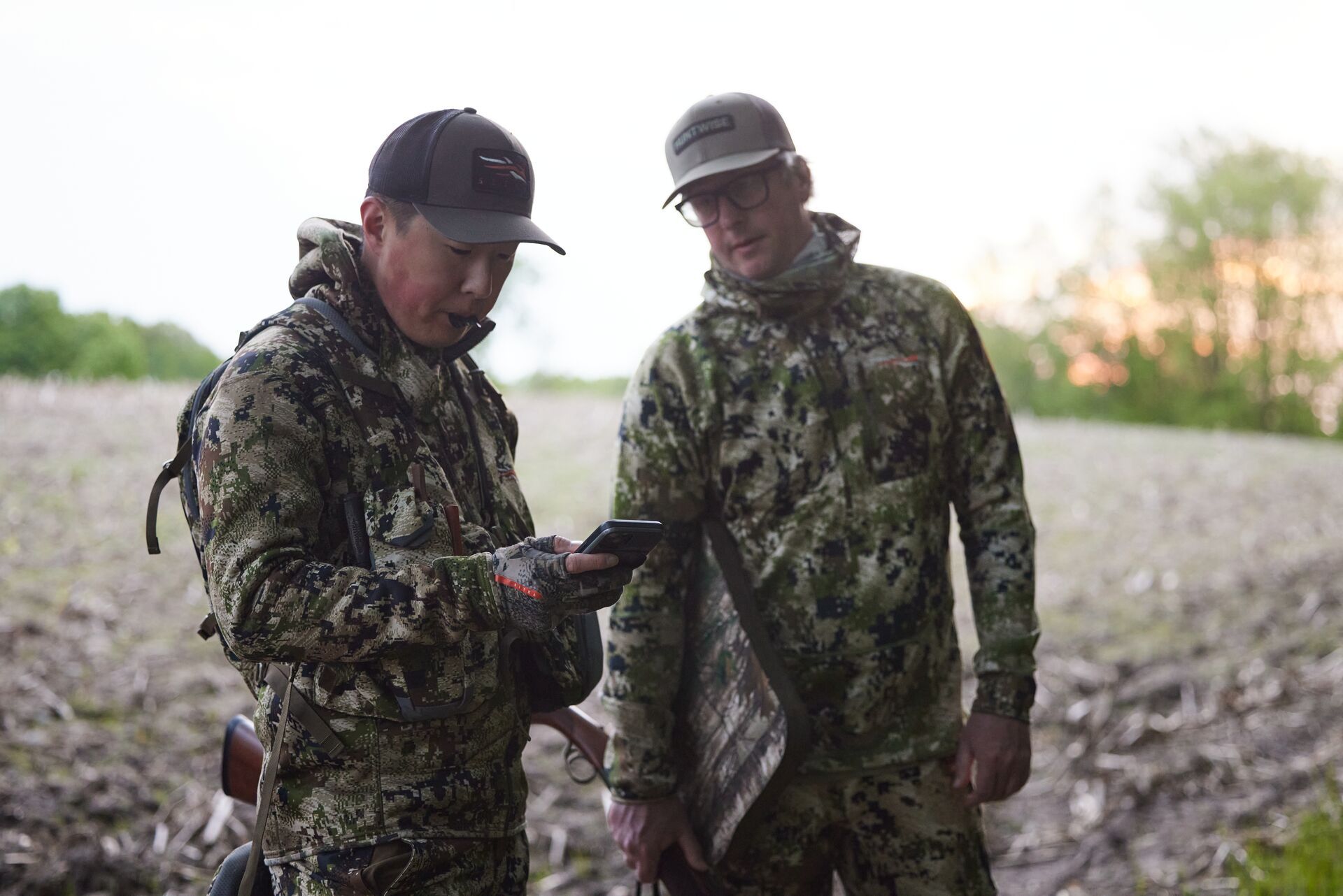 Two hunters look at a mobile phone to use HuntWise, hunting pack/back pack concept. 