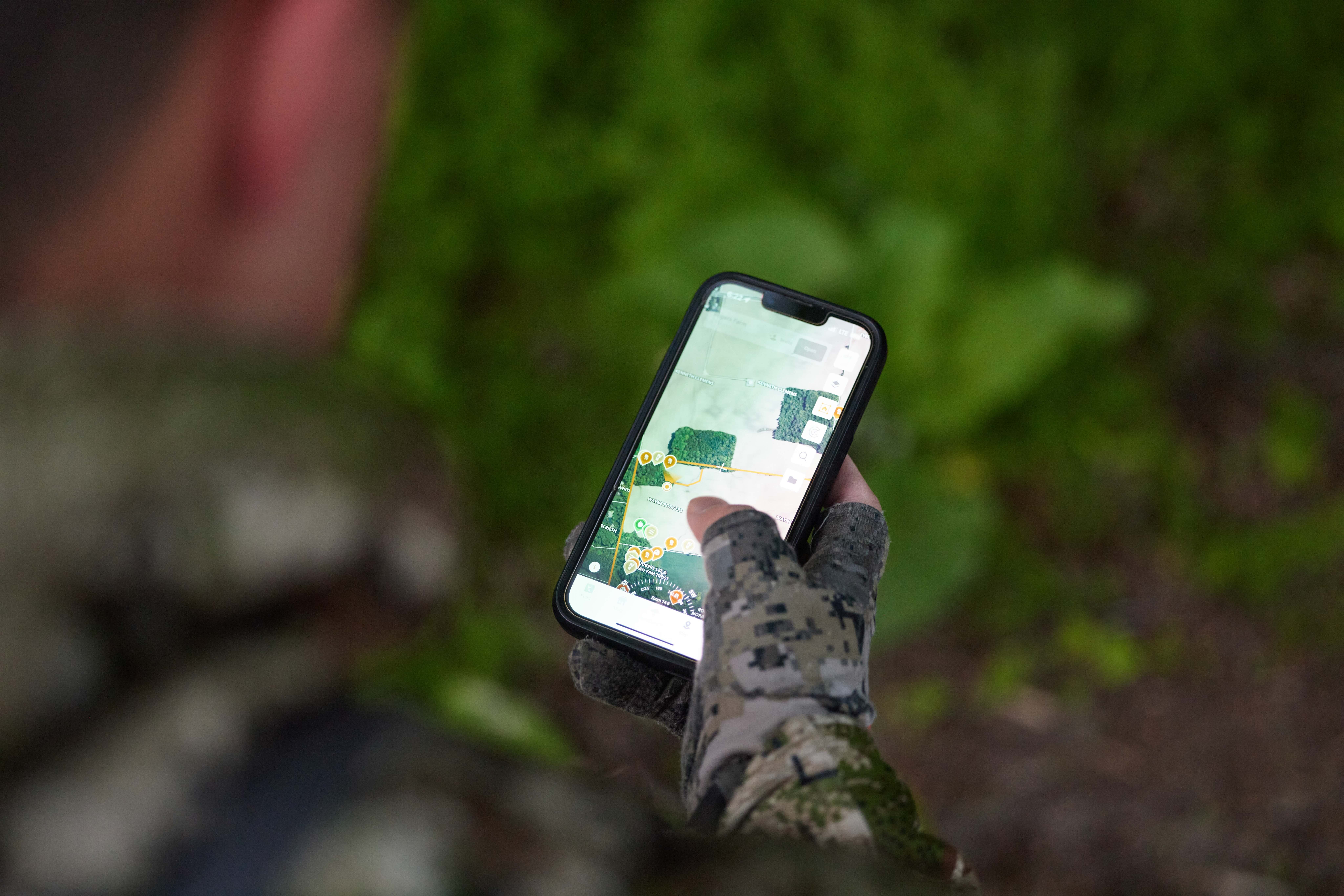 A hunter holding a phone with HuntWise on screen, find hunting land for deer season Florida concept.