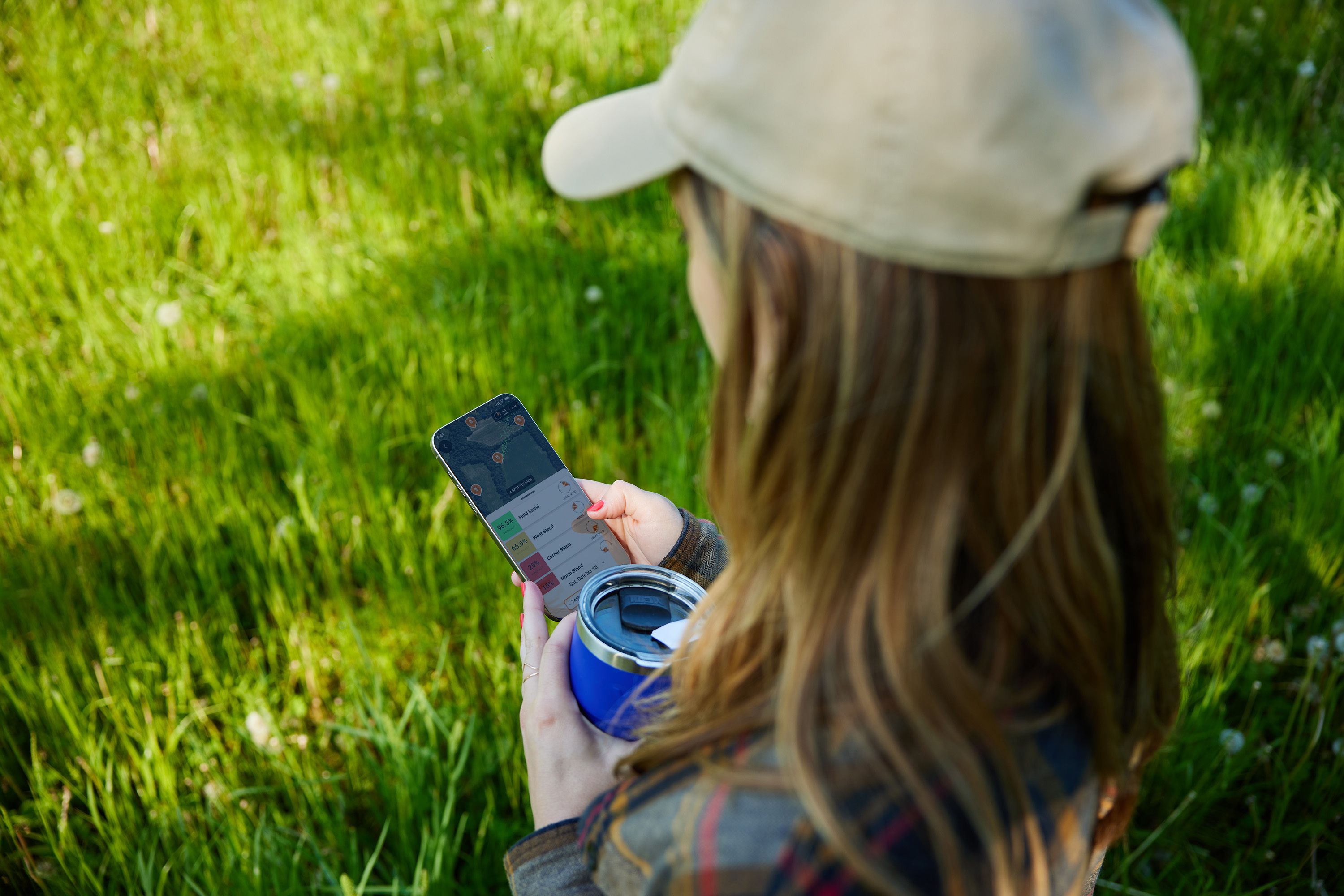 Close-up of a woman using a phone showing the HuntWise app, whitetail facts for hunting concept. 