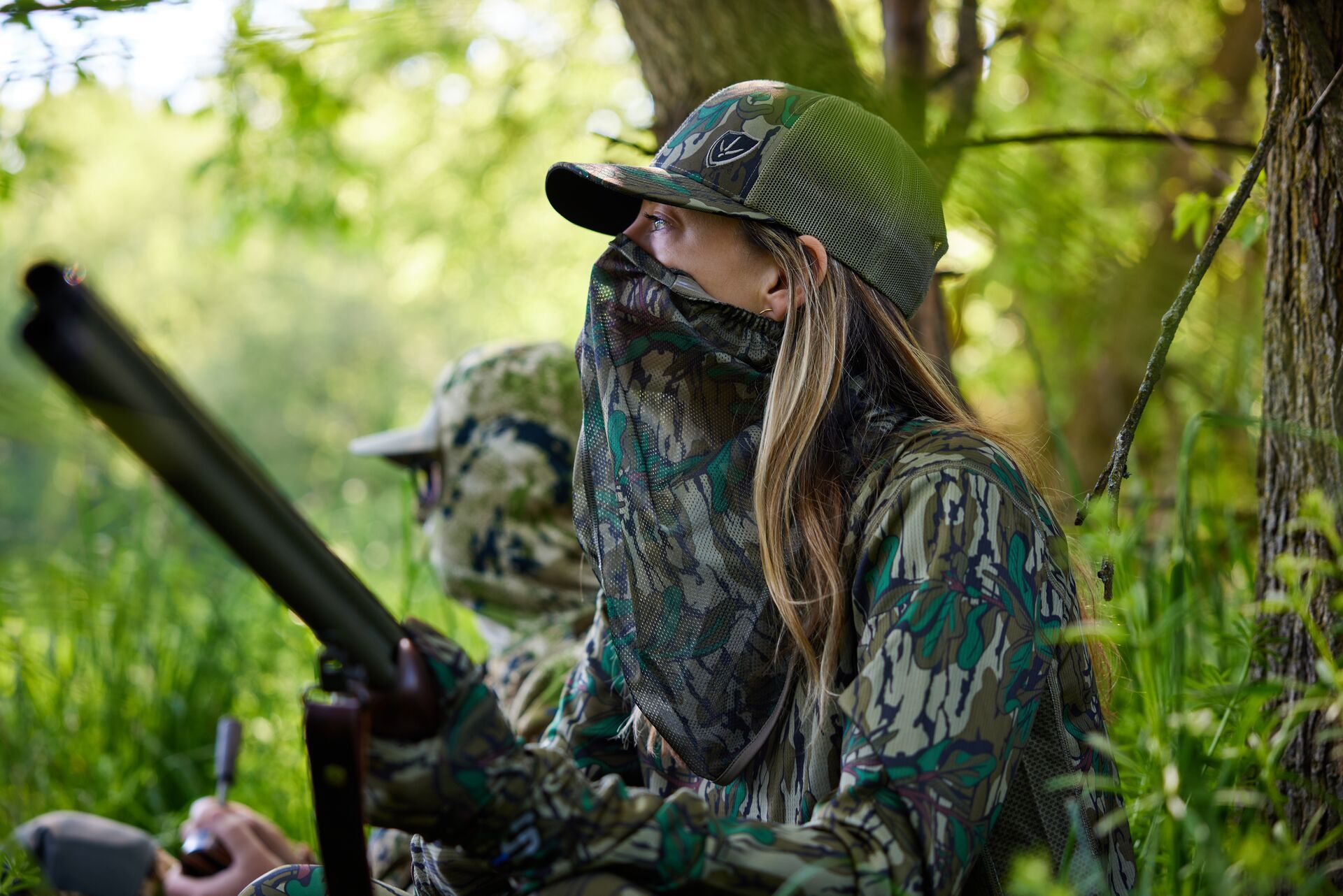 A man and woman in hunting camo sit in the woods, Florida turkey season concept. 