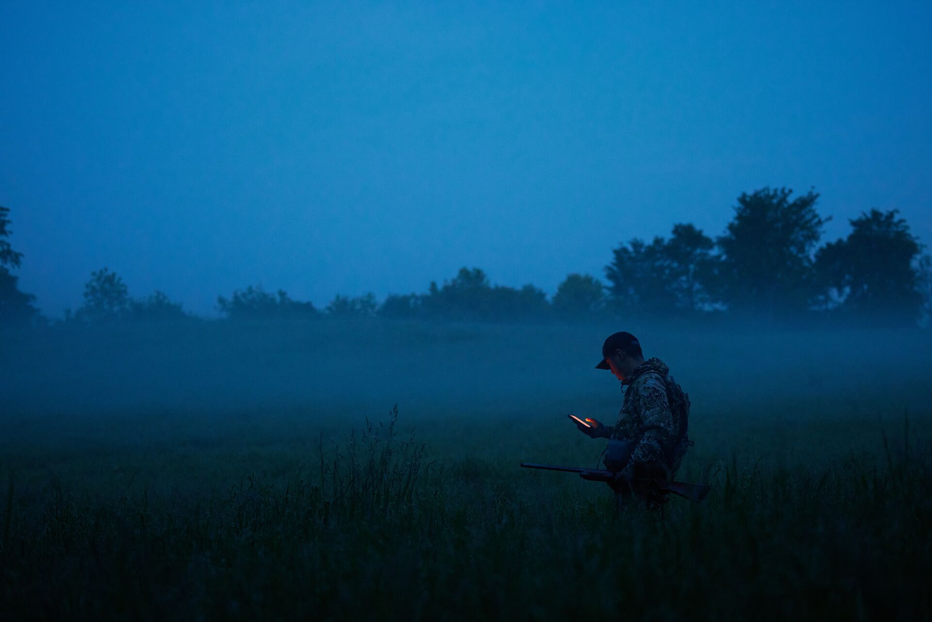 A hunter holding a phone to use HuntWise for whitetail deer hunting. 