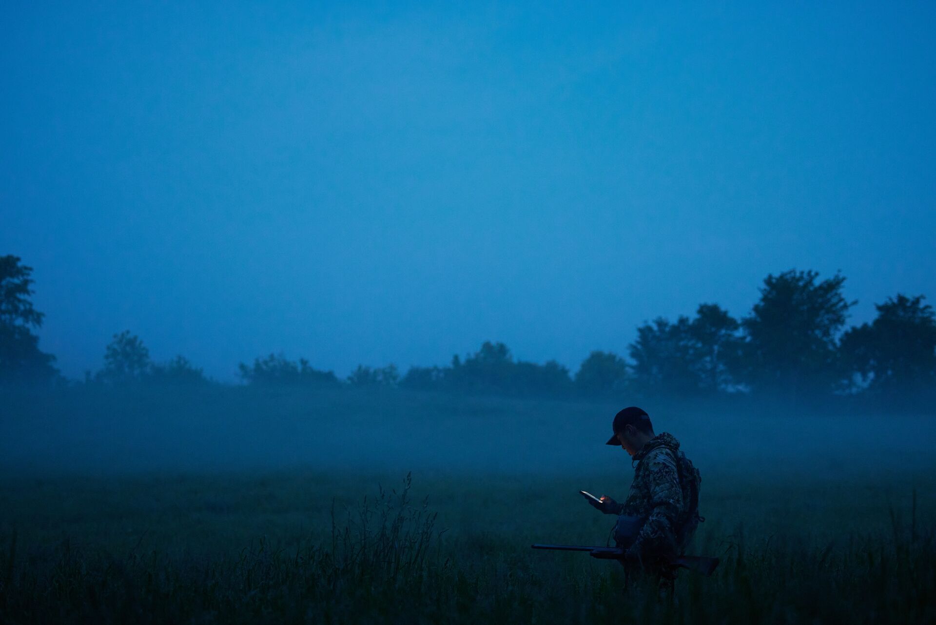 A hunter using the HuntWise app at dawn, using deer calls concept. 