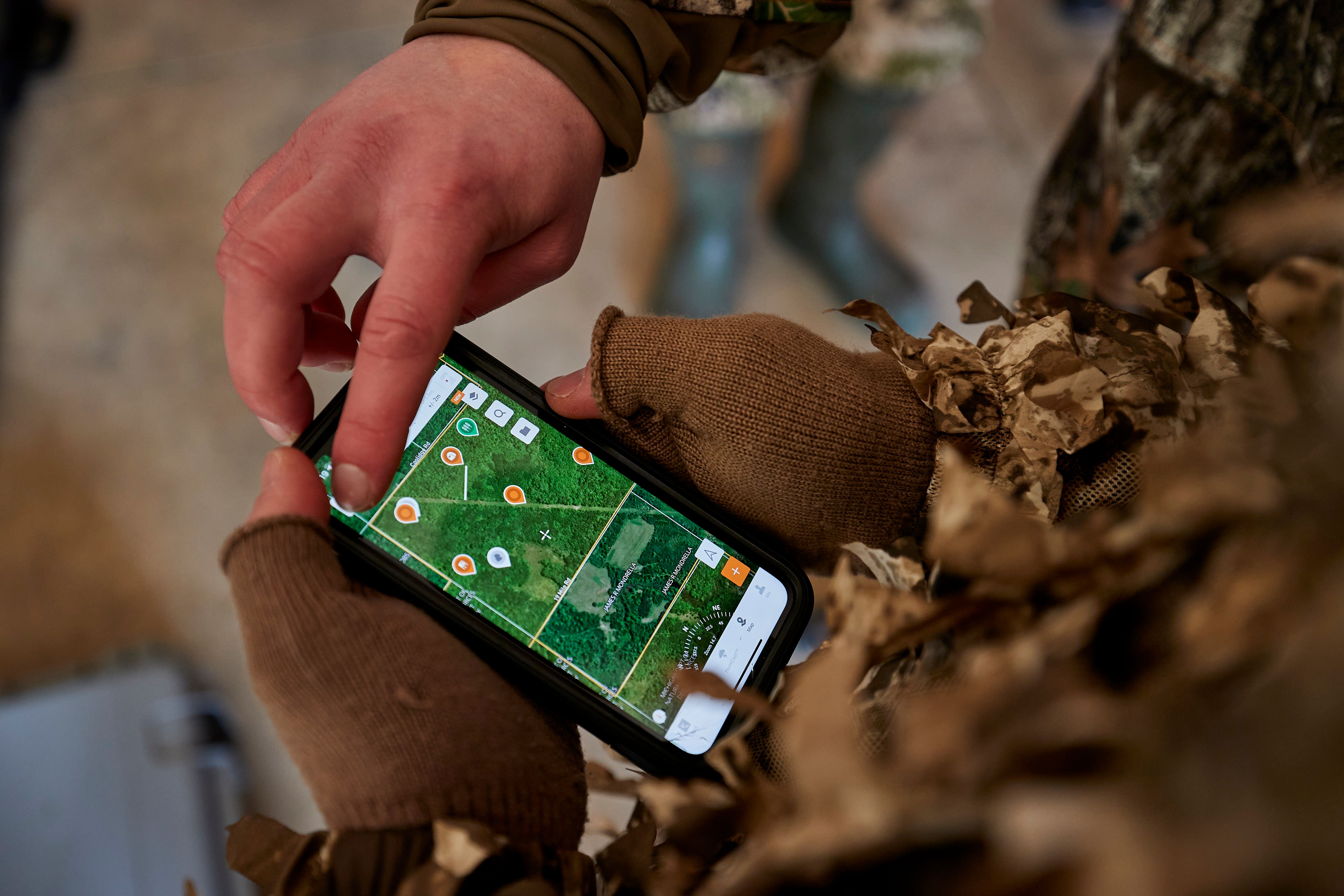 Close-up of hunters hands using the HuntWise app, hunting must-haves concept. 