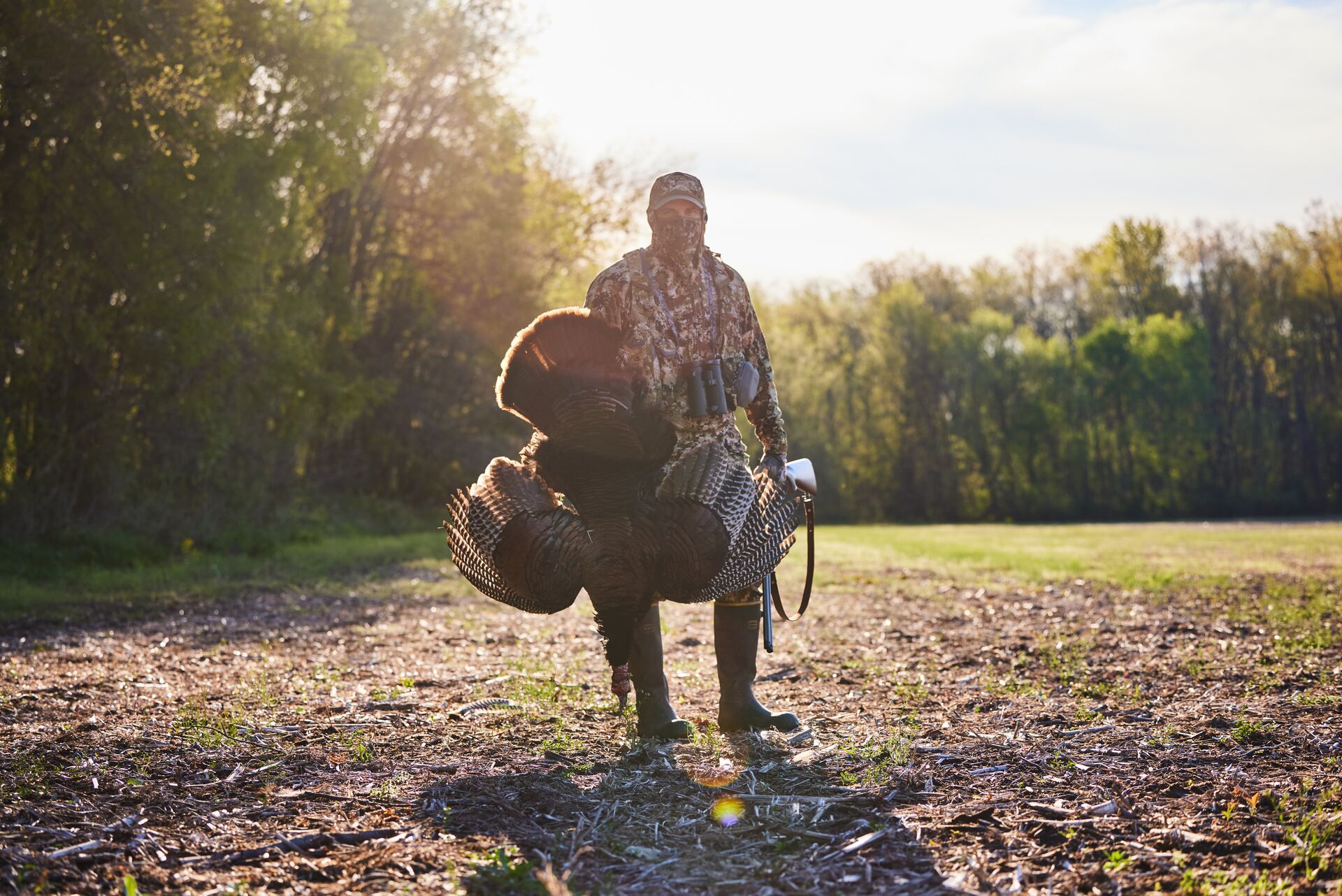 A hunter in camo holds a turkey after a hunt, hunting Easter turkey concept. 