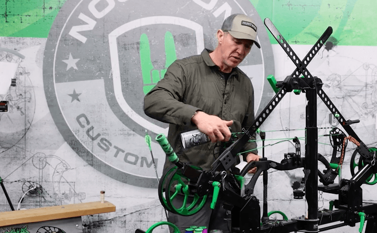 John Dudley using a can of compressed air to remove debris from a compound bow cam. 