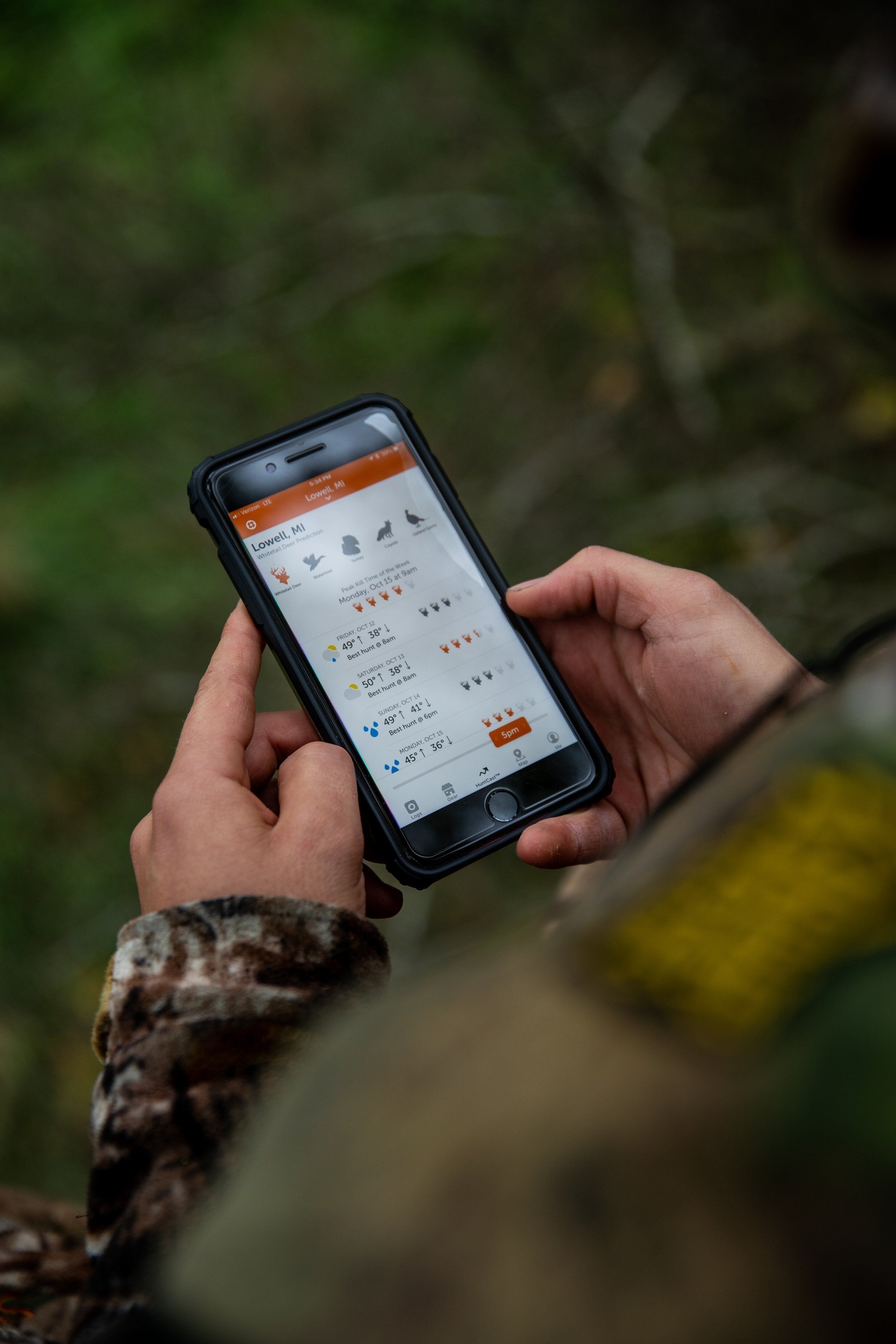 Close-up of a hand using a phone with the HuntWise app on screen, hunt the whitetail rut concept. 
